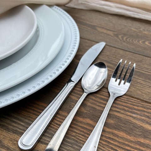 A close up of a fork, knife, and spoon on a rustic farm table for a wedding rental in Denver Colorado